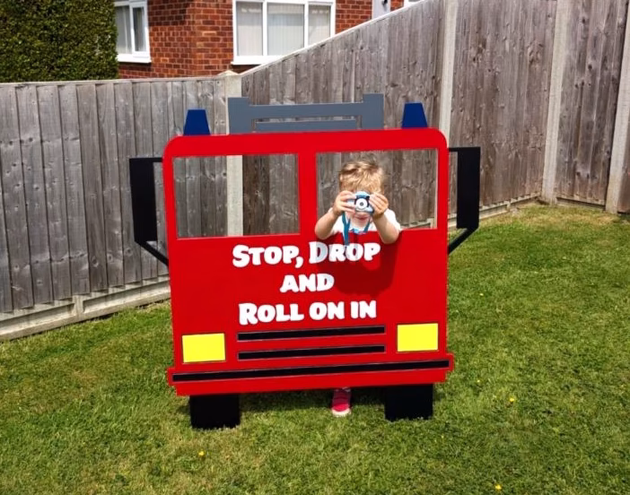Custom fire engine welcome sign party prop with "Stop, Drop And Roll On In" message - perfect for themed children's birthday parties in Norfolk by Williams and Rose