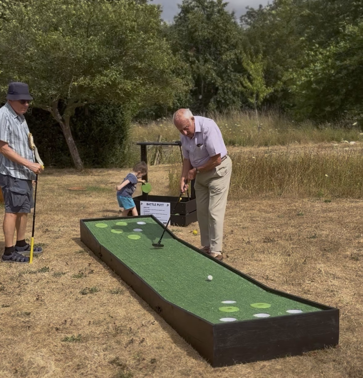 four generations of family playing garden game Battle Putt