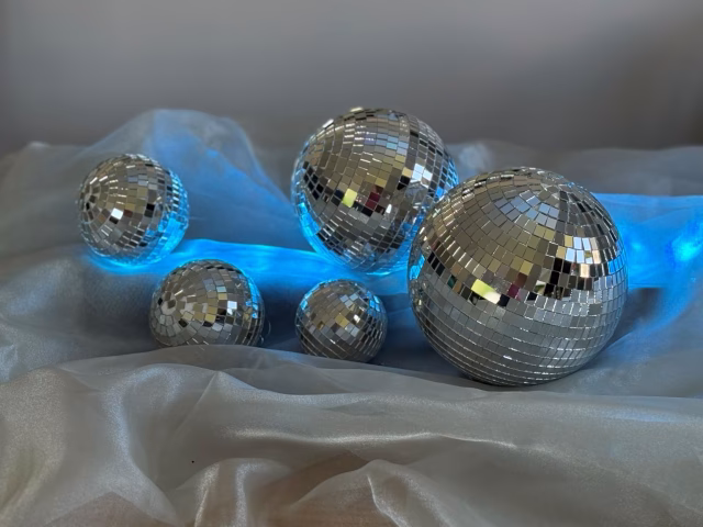Mirrorballs illuminated with blue lighting for contemporary event styling.
