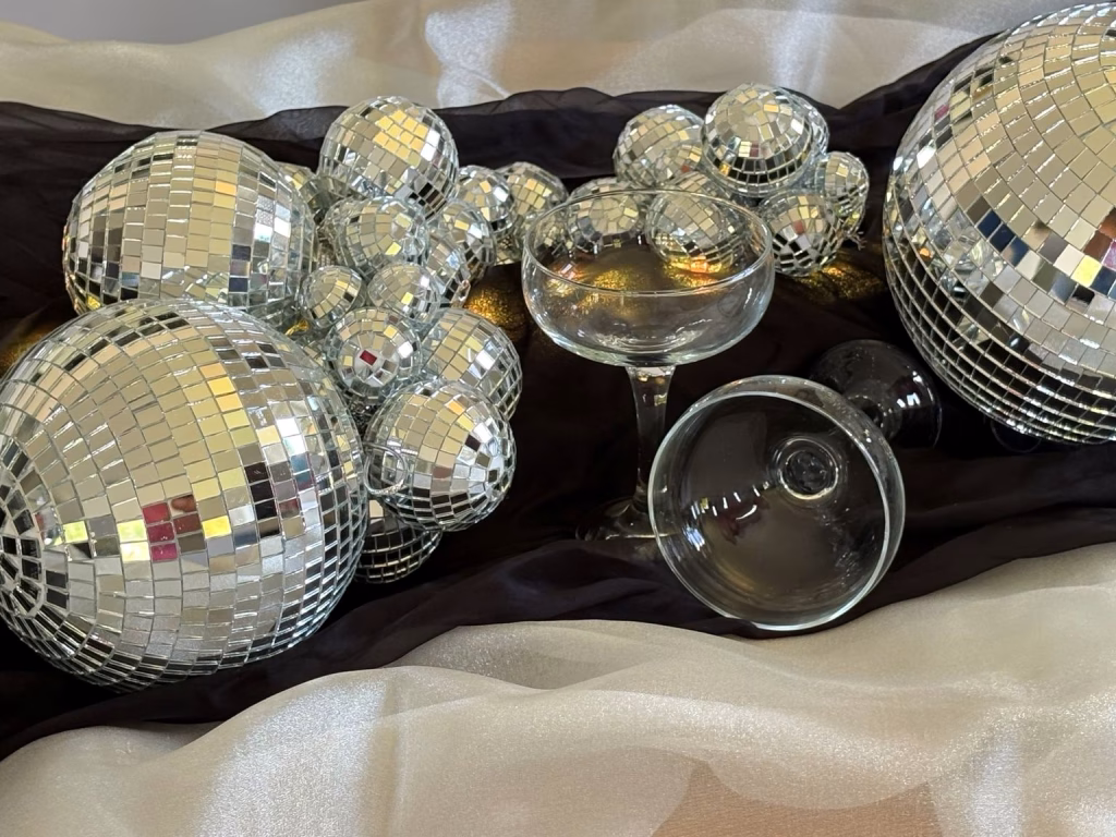 Signature mirrorball cluster styled with champagne coupes for a luxury event display.