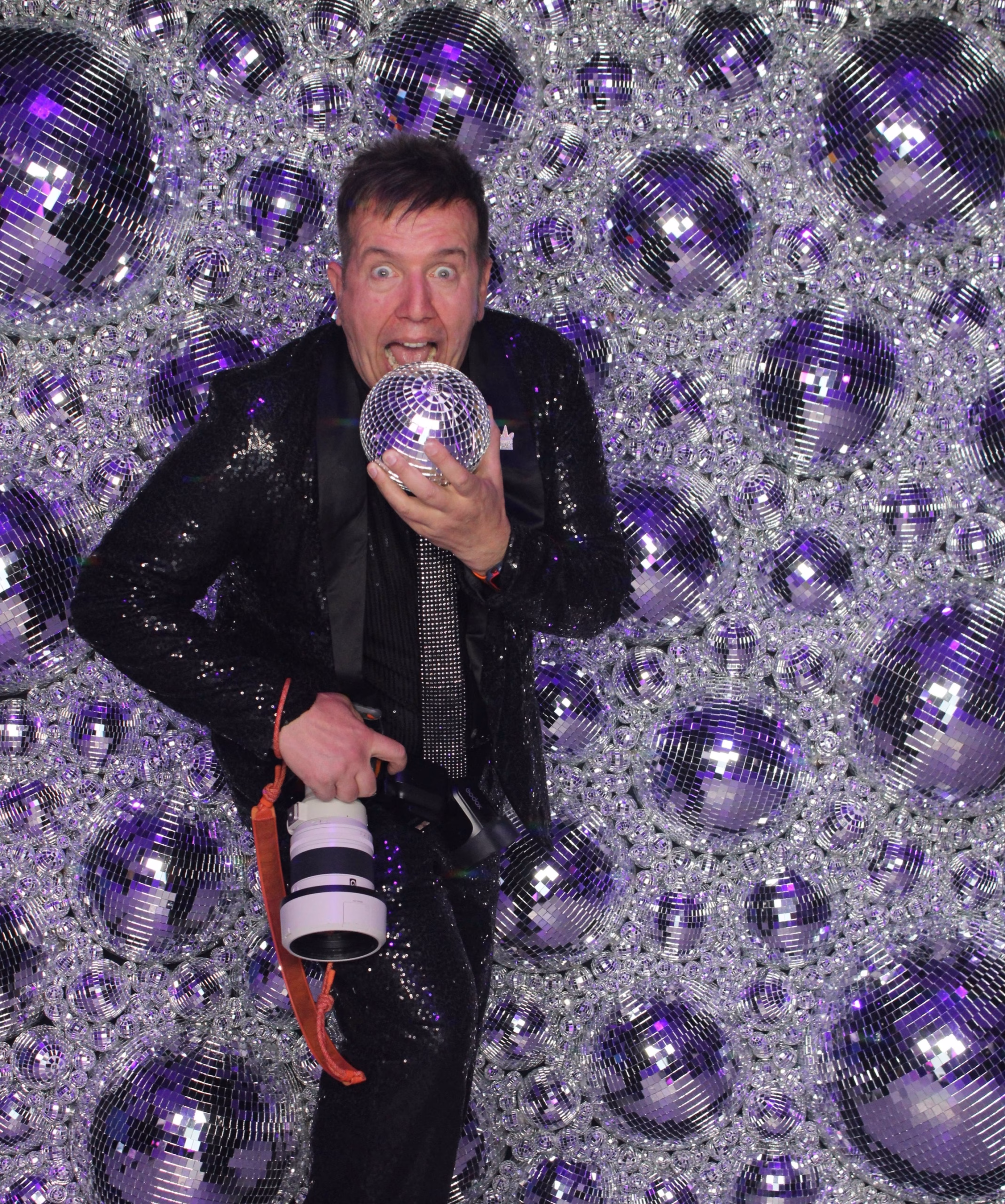 Guest posing with the Mirror Booth in front of the handcrafted Disco Ball Wall backdrop.