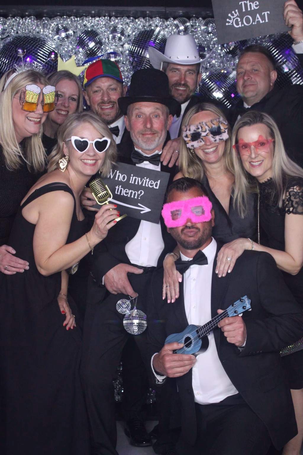 Large group of Guests at the Glitter Ball enjoying the mirror photo booth while posing in front of the Disco Ball wall