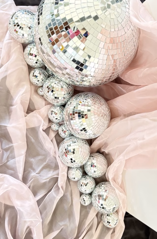 Cascading mirrorball arrangement styled with blush chiffon and black fabric for elegant wedding styling.