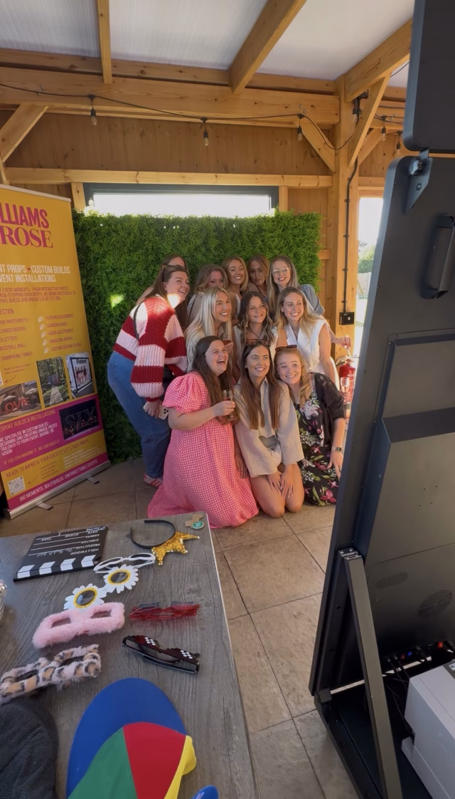 Guests enjoying the Williams & Rose Mirror Booth at the Norfolk Edit Creator Network event, with a green hedge backdrop and interactive photo booth experience in Norfolk.