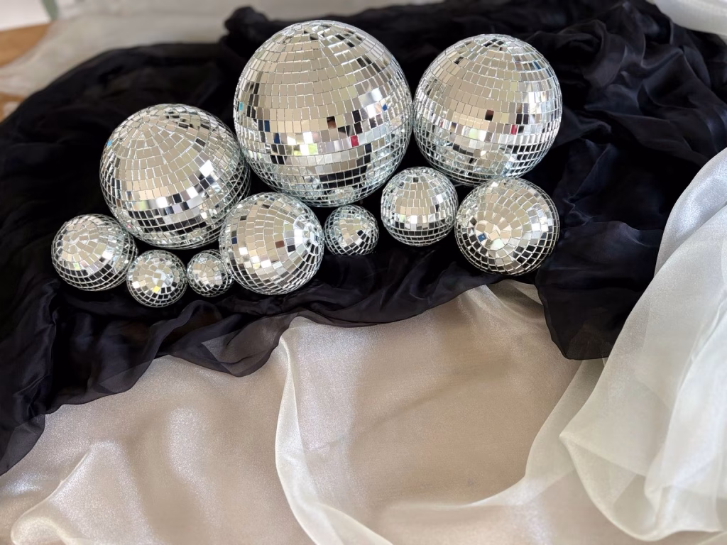 Mixed-size mirrorball collection styled on black chiffon and white shimmer fabric for luxury wedding and event décor.