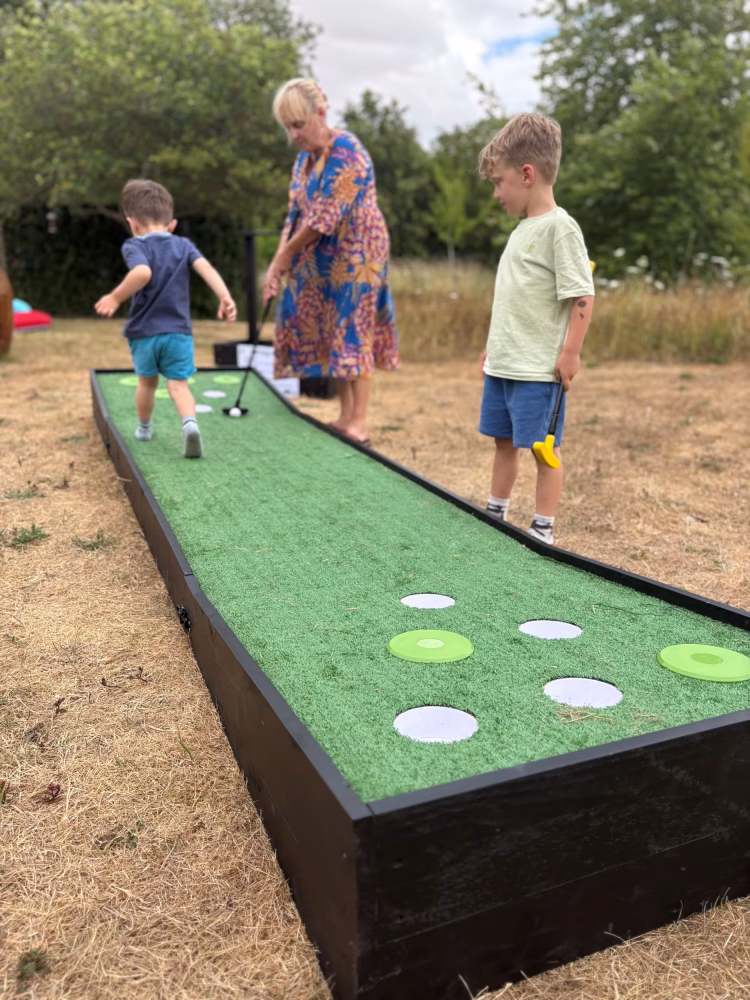 Children playing a portable crazy golf game in a garden setting
